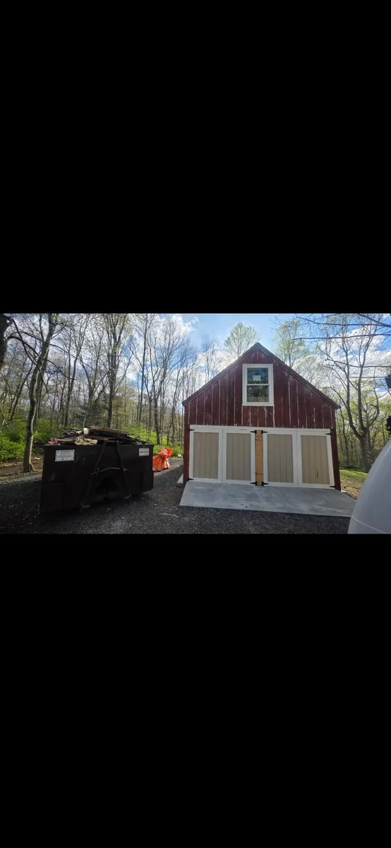 Weathered red barn with peeling siding and faded doors before repainting