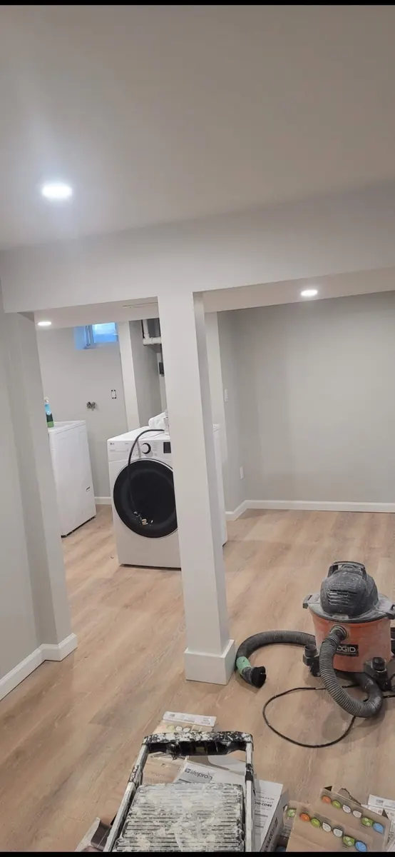 Finished basement with clean painted walls and new light wood flooring