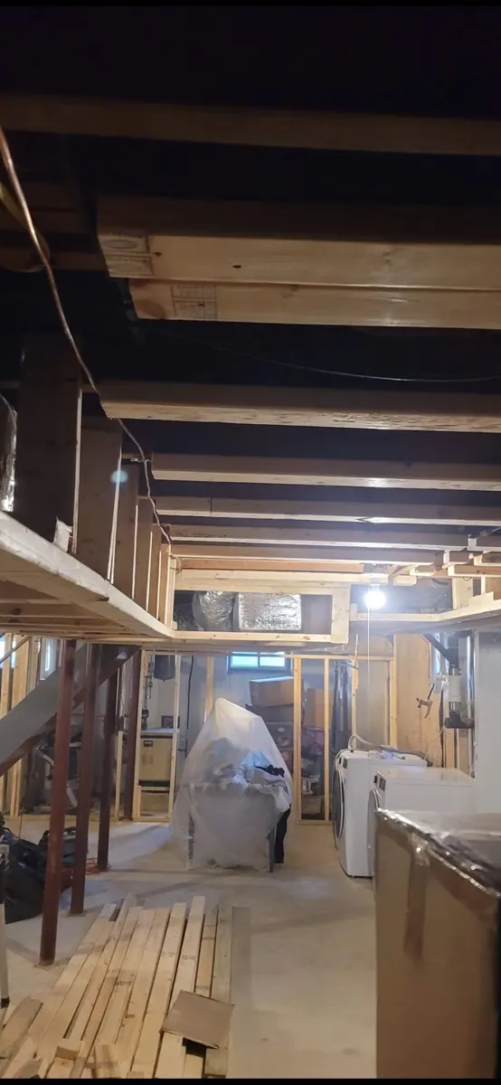 Basement work area with unfinished concrete floor and exposed framing