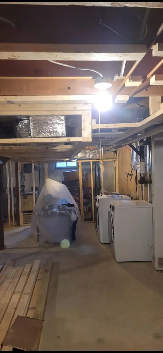 Unfinished basement with exposed ceiling framing and stored materials