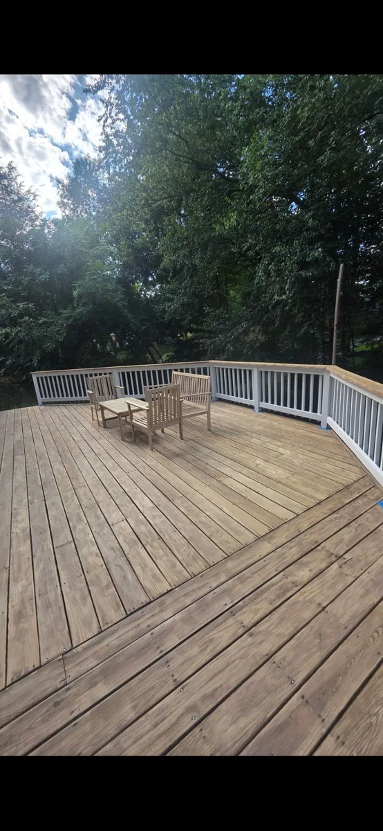 Weathered wood deck with bare boards and white railing before staining