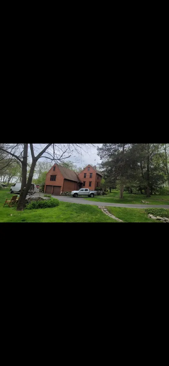 Side view of a brown and cedar-sided home before painting