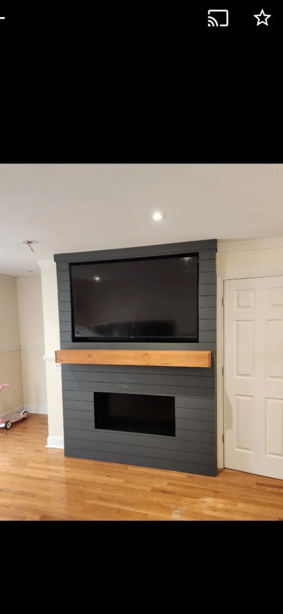 Finished charcoal shiplap fireplace and media wall with a natural wood mantel